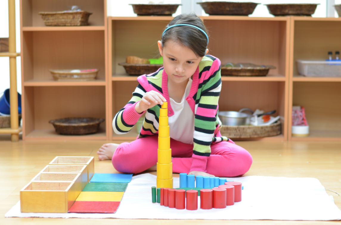 A Lower Elementary student exploring a Montessori lesson on the floor