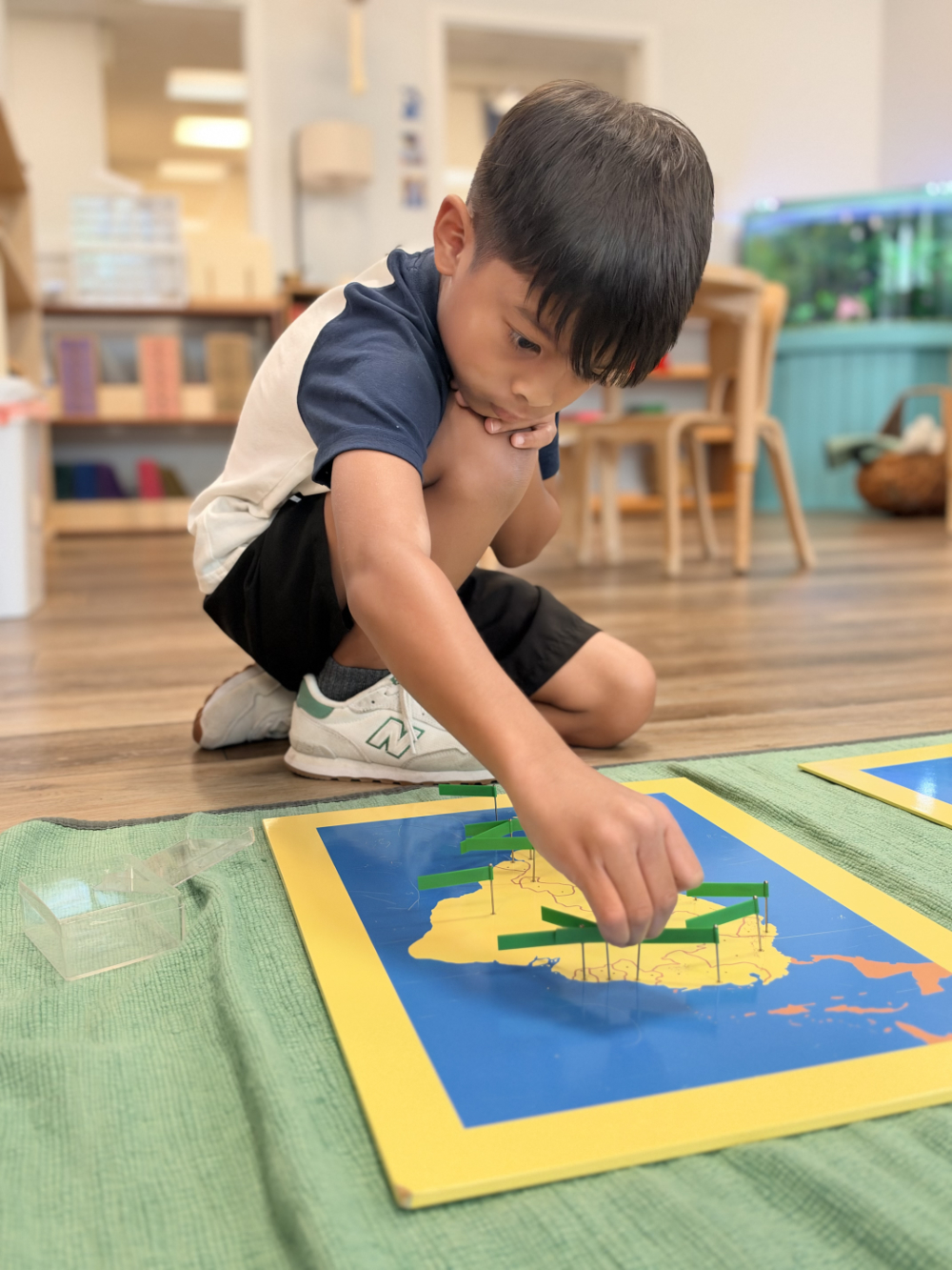 A Lower Elementary student exploring a Montessori lesson on the floor