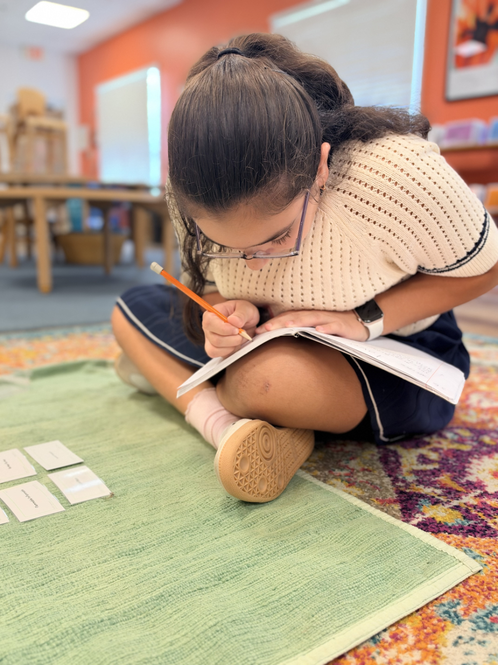 The hands of an Upper Elementary student working on classroom work